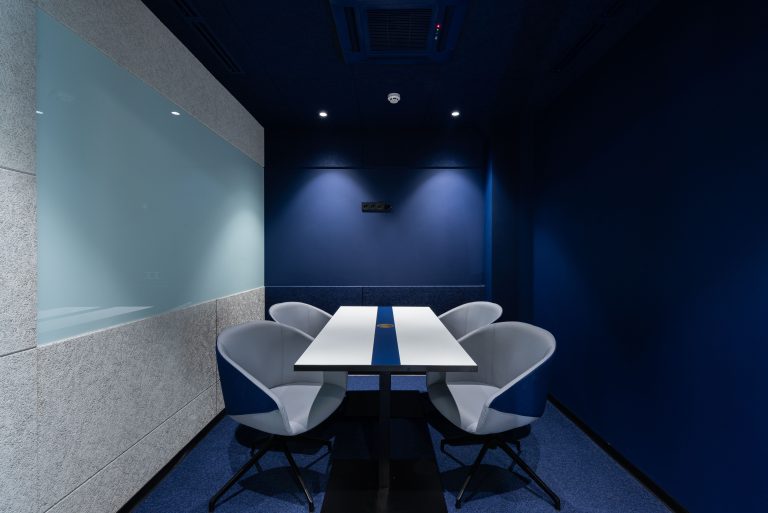 Blue conference room with four chairs and a white table