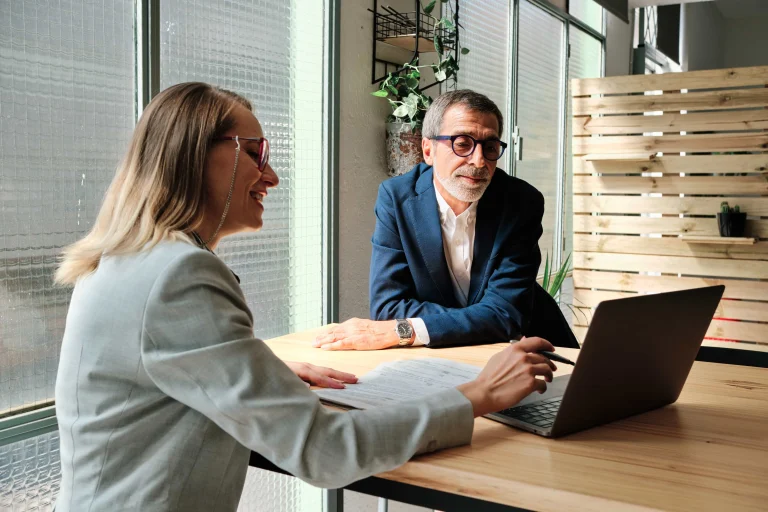 Two people review financial information together at a bright office desk