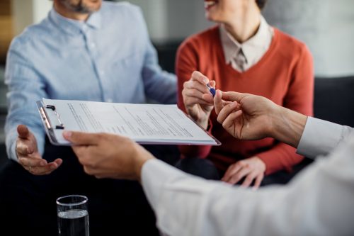 Close-up of unrecognizable couple signing a contract with financ