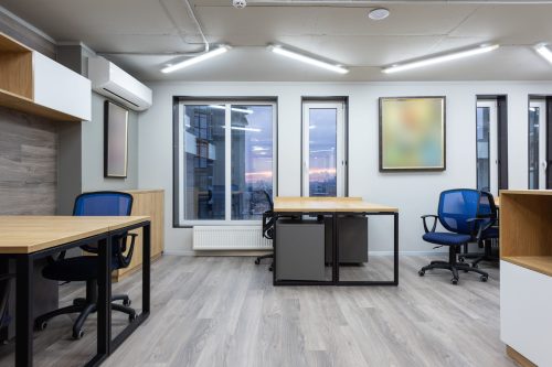 Desks and blue chairs in an office at dusk