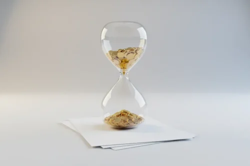Glass hourglass with coins flowing onto a tidy stack of blank invoices against a soft neutral background.
